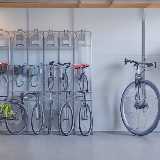 A clutter-free garage with a sleek, silver bike rack mounted on a gray wall, holding two mountain bikes, and a nearby row of five translucent storage bins labeled with colored tabs.