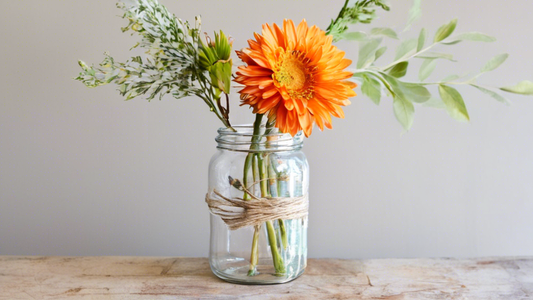 Create an image of a step-by-step guide for turning an empty glass jar into a decorative vase using materials commonly found at home. The image should show the process from start to finish, with clear and simple instructions at each step for a beginn